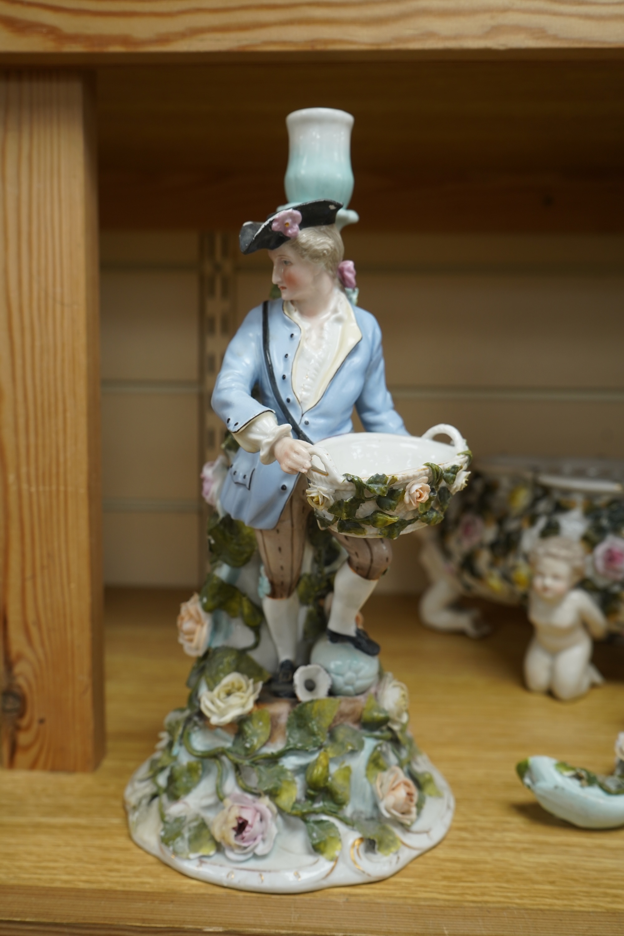 A German flower encrusted porcelain figural candelabrum, 30cm high, a cherub jardiniere and a cherub vase, all encrusted